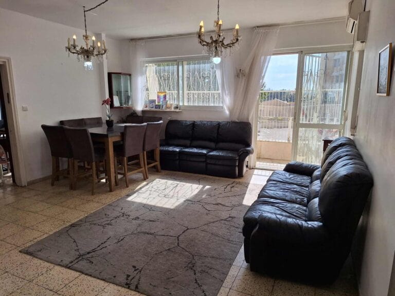 Dining table, chandeliers and black leather sofas in the Hakalir 4-bedroom apartment in Rechavia, Jerusalem.