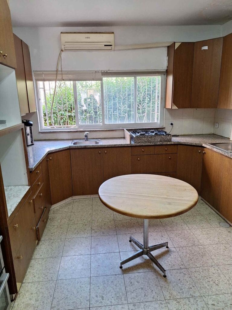 Round breakfast table beside the kitchen window in the Hakalir 4-bedroom apartment in Rechavia, Jerusalem.
