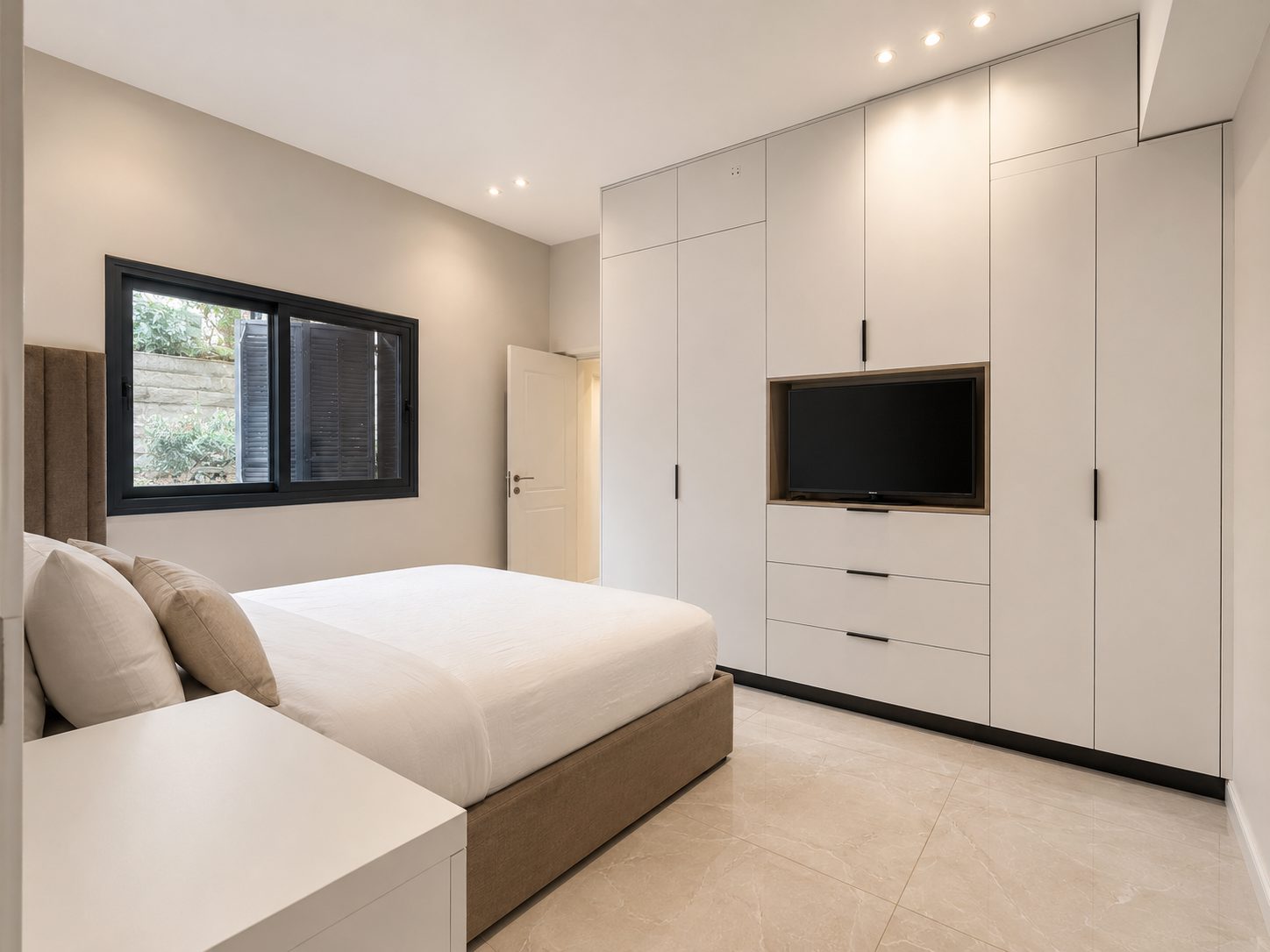 Primary bedroom with built-in closet and television in the Ramban Luxury Rechavia apartment