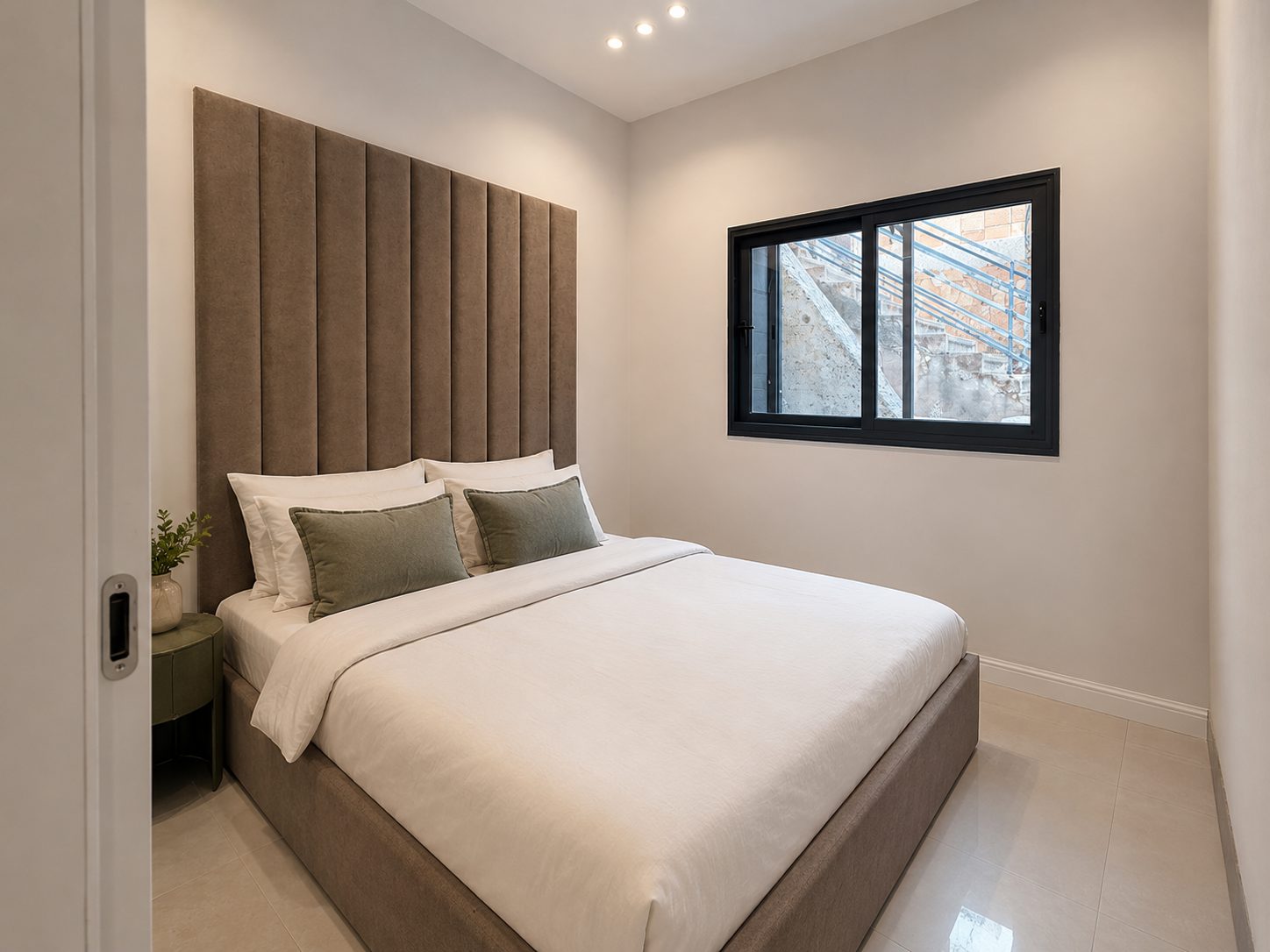 Double bedroom with upholstered headboard and window in the Ramban Luxury Rechavia apartment