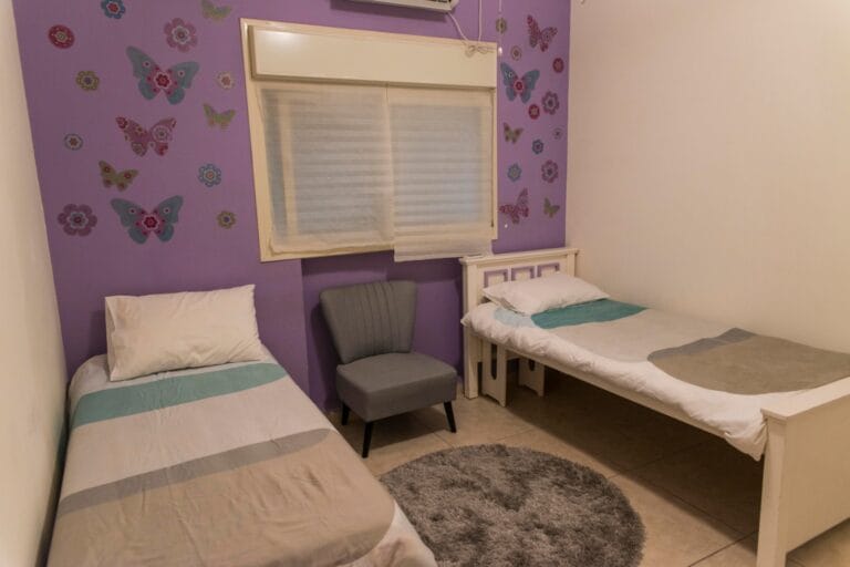 Twin bedroom with a purple butterfly feature wall and two individual beds at Ramban Giant Sukkah Apartment, Jerusalem