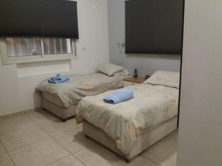 Main bedroom with two separated beds and a bedside cabinet between them at Ramban Giant Sukkah Apartment, Jerusalem
