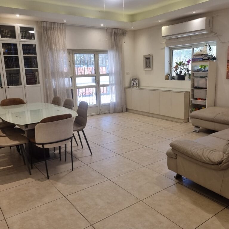 Living and dining room with glazed courtyard doors and wall-mounted air conditioning at Ramban Giant Sukkah Apartment, Jerusalem
