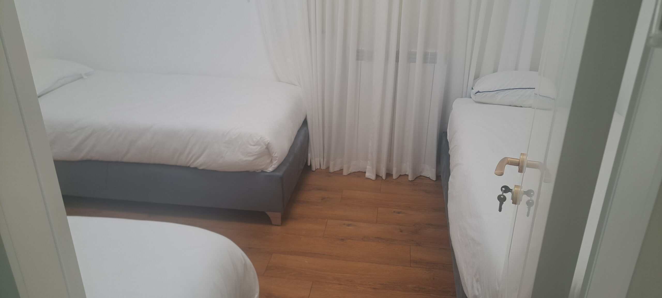 Bedroom with three separate beds and wood flooring at Wolfson Villa in Jerusalem.
