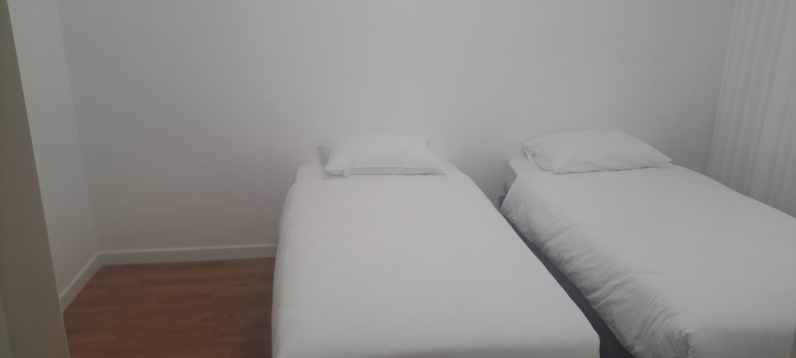 Twin guest bedroom with two separate beds and wood flooring at Wolfson Villa in Jerusalem.