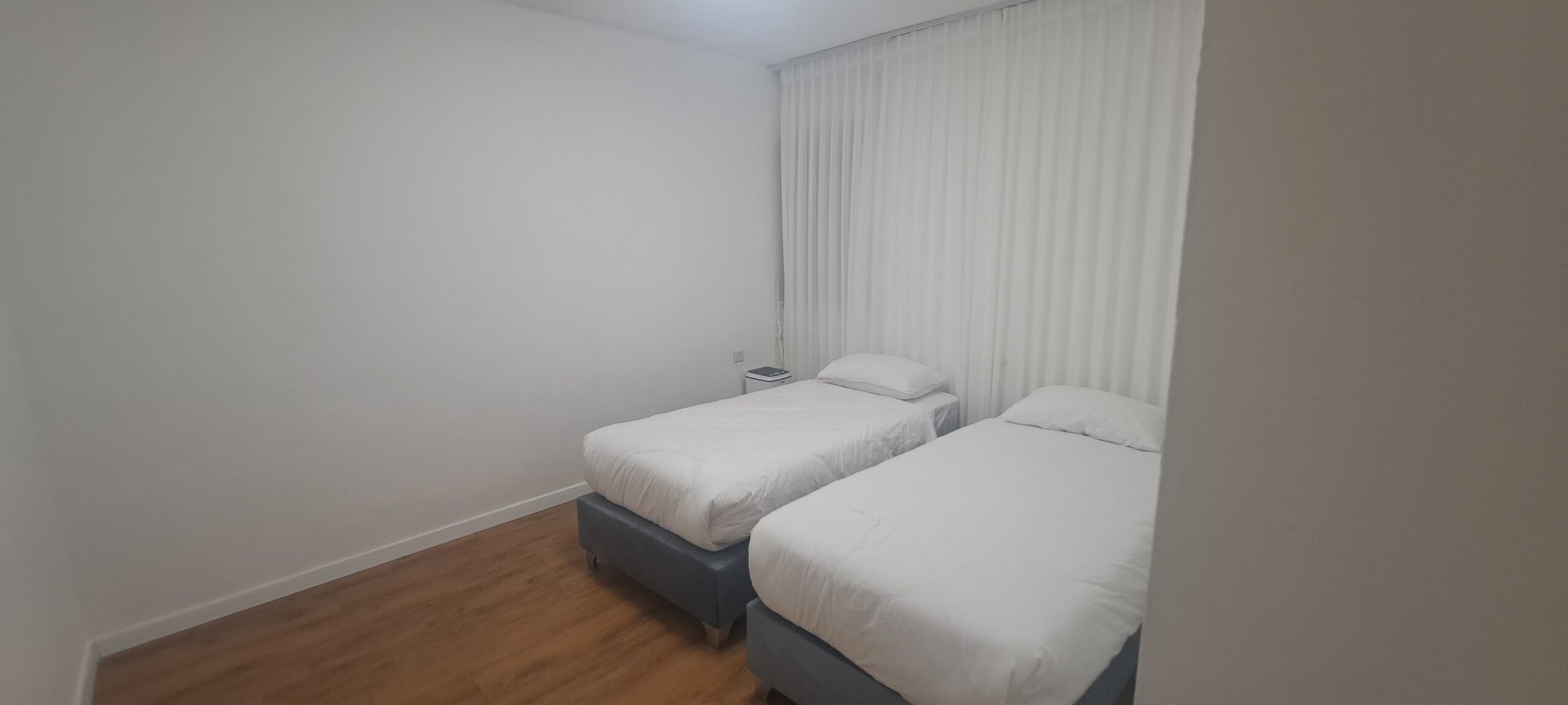 Twin bedroom with two separate beds and wood flooring at Wolfson Villa in Jerusalem.