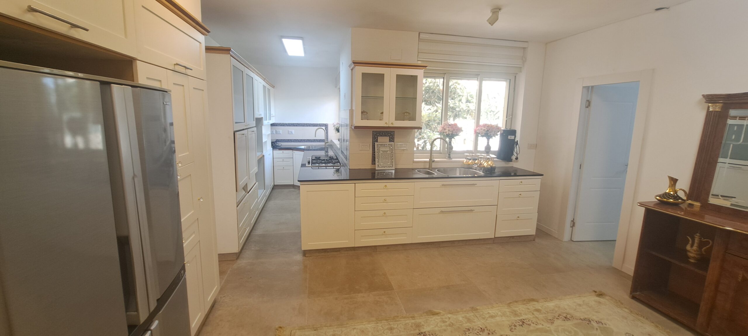Large kosher main kitchen with island, extensive cabinetry and full-size refrigerator at Wolfson Villa in Jerusalem.
