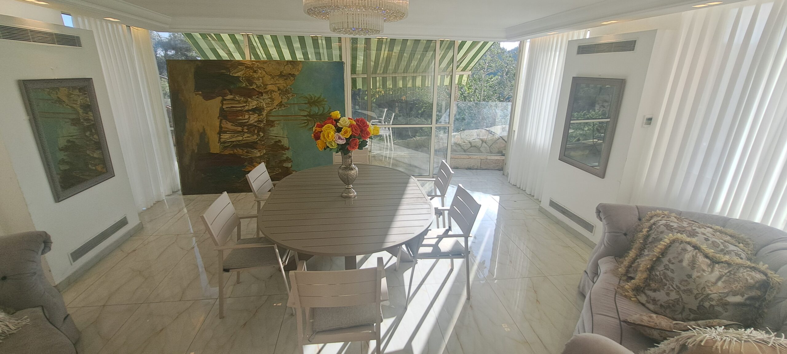 Sunlit family dining room beside the panoramic garden windows at Wolfson Villa in Jerusalem.