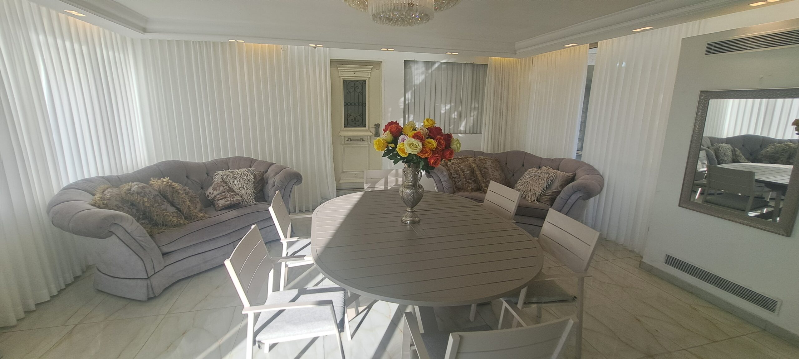 Bright reception and dining room with sofas and a large family table at Wolfson Villa in Jerusalem.