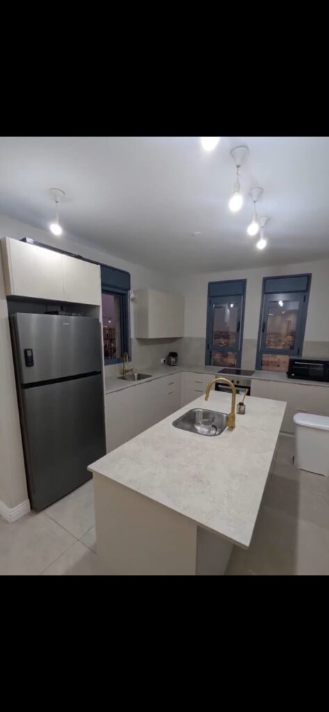 Kitchen with island, two sinks and refrigerator at the Navon apartment in Mekor Baruch