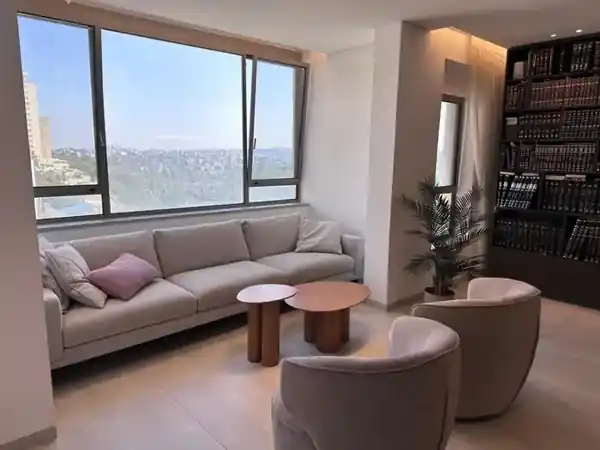 Contemporary living room with large picture window and panoramic Jerusalem view in the Ben Tzvi Rechavia apartment by Gan Sacher.