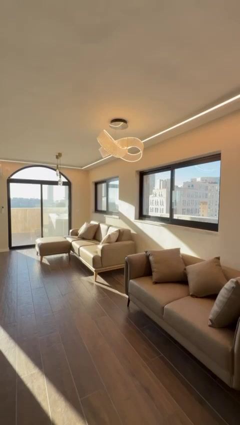 Sunlit living room with two sofas and terrace access in the Eliash Street penthouse, Jerusalem