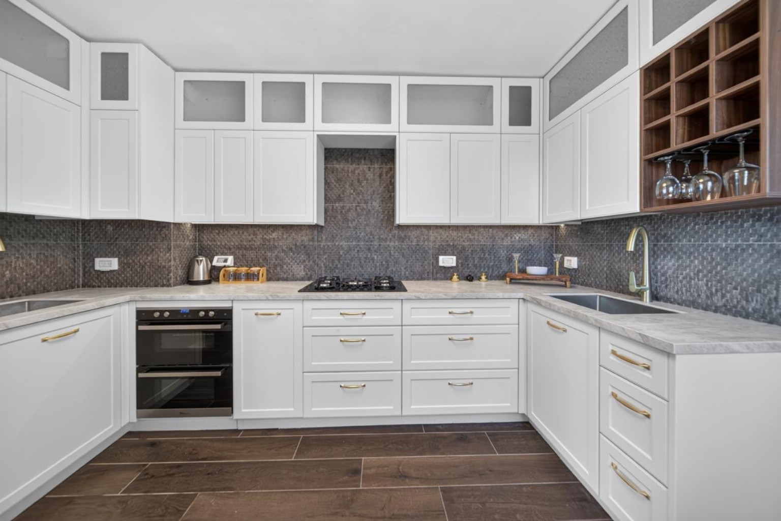 Front view of the white penthouse kitchen with a double oven, gas cooktop and extensive storage