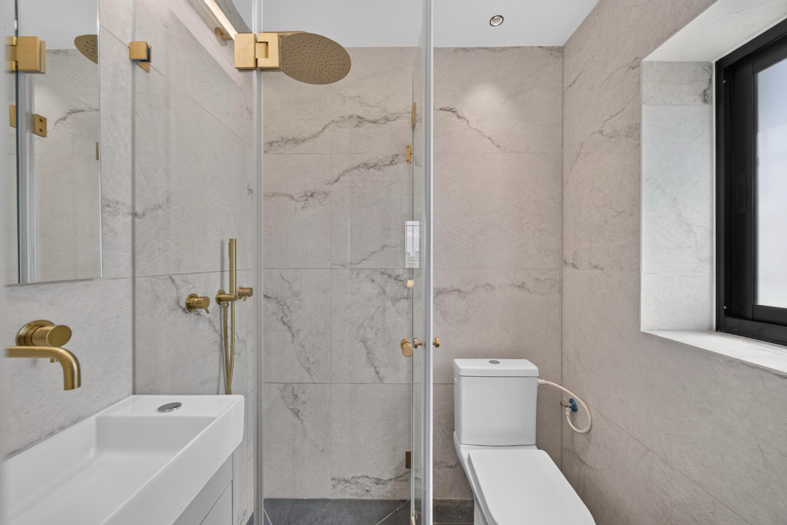 Marble-effect bathroom with rainfall shower, handheld shower and gold fixtures in Jerusalem