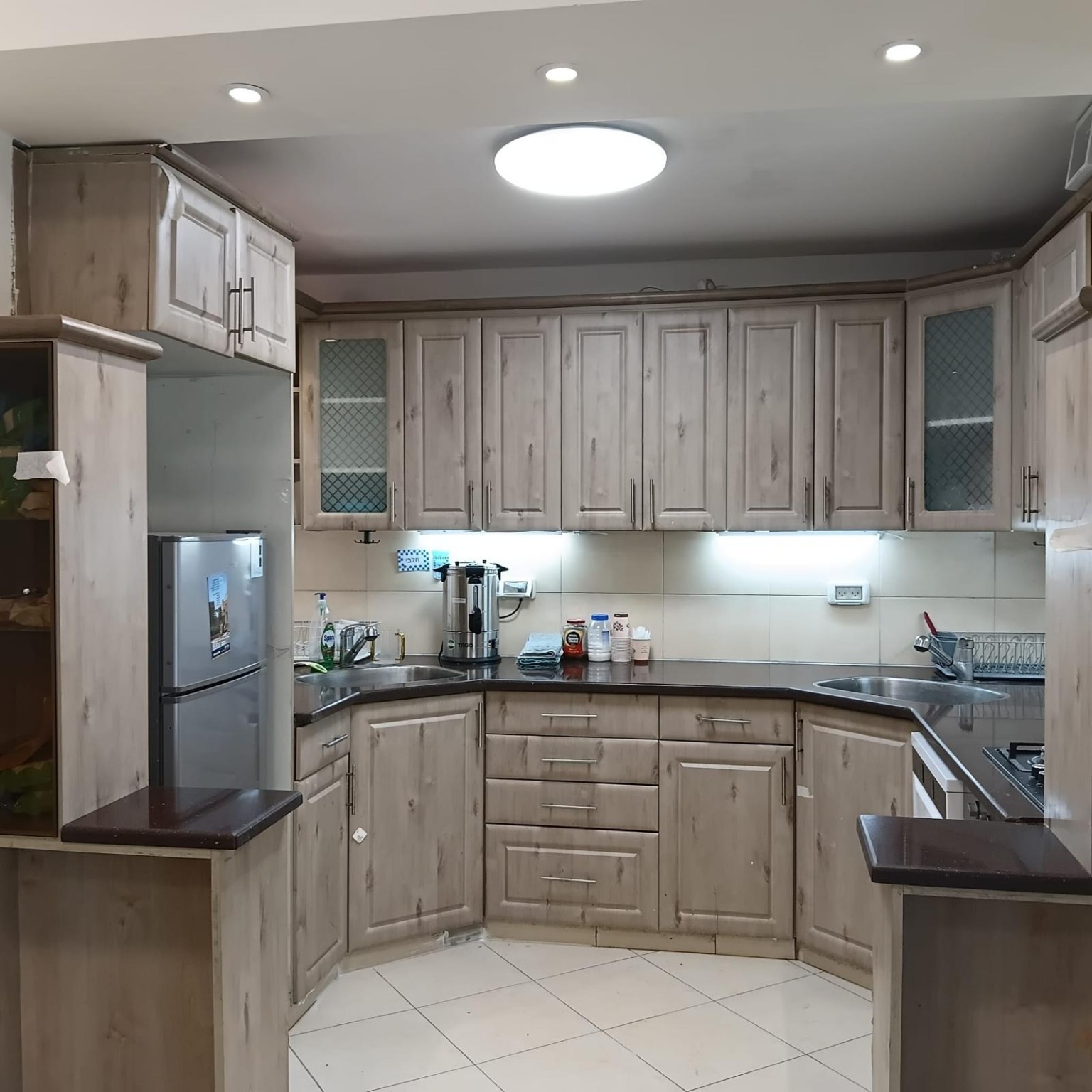 U-shaped kitchen with two sinks, pale cabinets and dark worktops at Ibn Shaprut Apartment #2