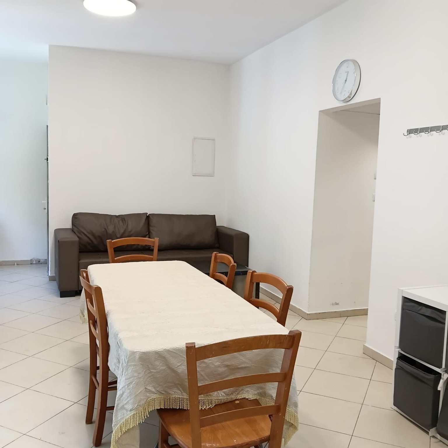 Dining table with wooden chairs and a brown sofa at Ibn Shaprut Apartment #2
