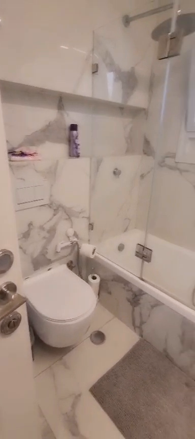 Bathroom with a toilet, bathtub, glass shower screen and overhead shower in the Ibn Shaprut apartment.