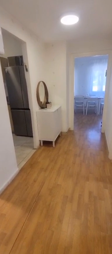 Hallway with a white console and round mirror leading toward the dining area in the Ibn Shaprut apartment.
