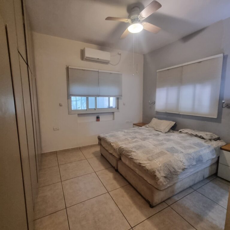 Main bedroom with two individual beds, air conditioning and ceiling fan at Ramban Giant Sukkah Apartment, Jerusalem