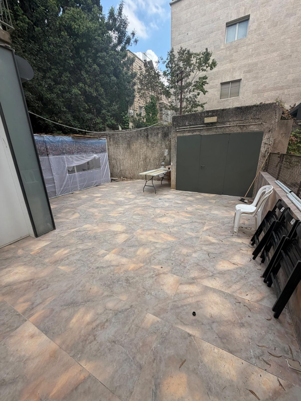 Paved private backyard courtyard with a sukkah, folding table and chairs at the Ramban Rechavia apartment.