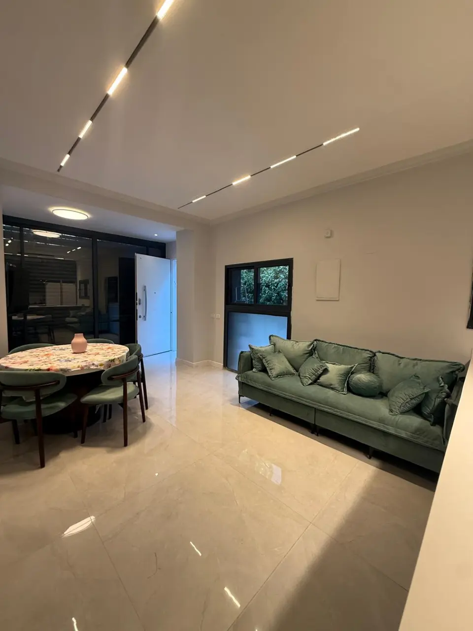 Bright living and dining room with green sofa in the Ramban Rechavia apartment