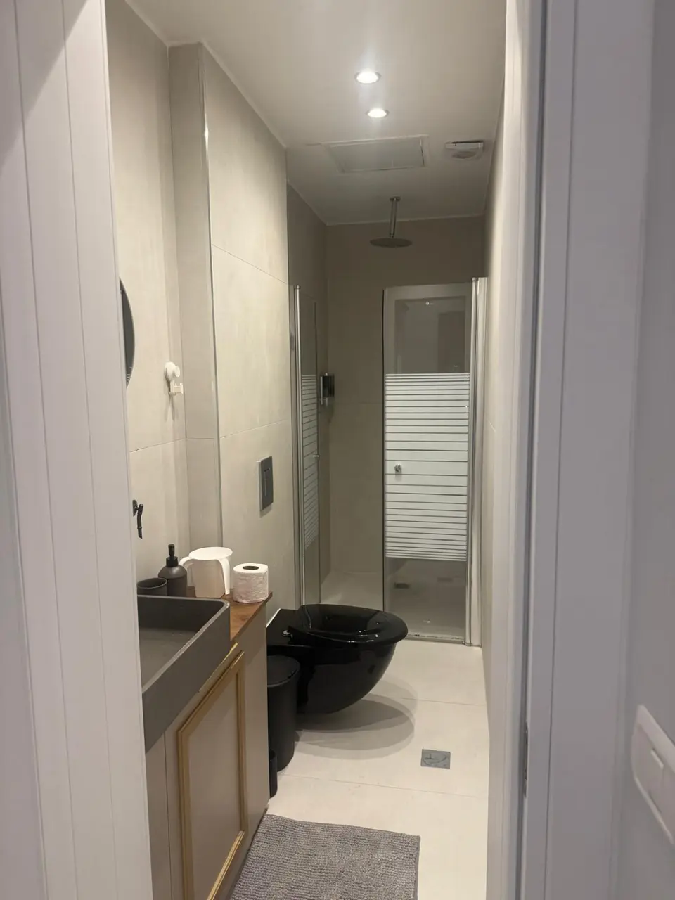 Modern bathroom with a glass-enclosed walk-in rain shower in the Ramban Rechavia apartment